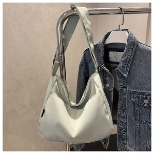 Detail of mint green hobo shoulder bag in nylon material hanging on a metal hanger