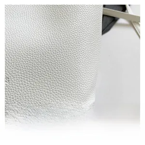 Détail macro montrant la texture grainée du cuir blanc sur un sac seau élégant pour femme