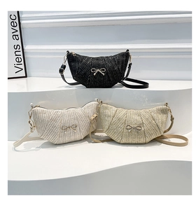 Detailed view of three crescent woven bags in black, white and khaki with metal bows