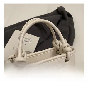 Close-up of white lychee pattern leather handbag featuring knotted handle and silver hardware