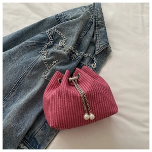 Détail du sac seau tissé rose avec bandoulière chaîne argentée et pompons en perles