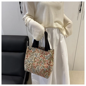 Close-up of floral pattern cotton linen tote bag with black woven handles in a cozy home setting