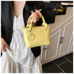 Detail of yellow lychee texture tote with smiley charm and fashion embossed text