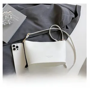 Vue détaillée du sac seau blanc en cuir grainé avec comparaison de taille smartphone
