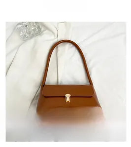 Top view of caramel brown baguette bag with golden buckle on white fabric background