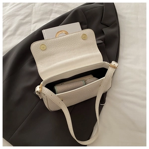 Detail view of white croc-embossed bag interior with magnetic closure and items