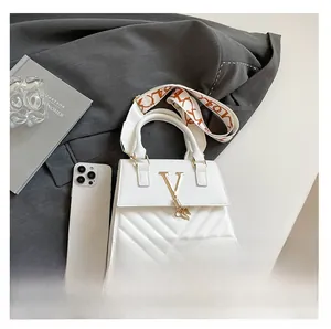Macro detail of white quilted crossbody bag with metal V-buckle and patterned strap