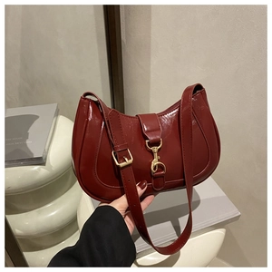 Détail du sac à bandoulière en cuir verni bordeaux brillant avec boucles dorées chic