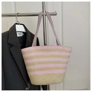 Close-up of pink and beige striped straw woven tote bag texture and fabric straps