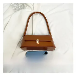 Detailed size comparison of the brown baguette bag with a smartphone on white fabric