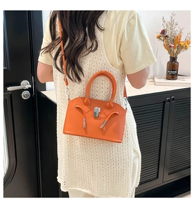 Oranje schelptas met lycheepatroon gedragen als crossbodytas in een stijlvol interieur