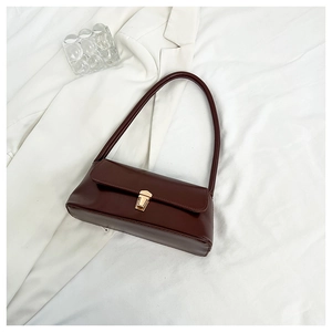 Detail view of deep brown glossy leather baguette bag with elegant golden snap closure