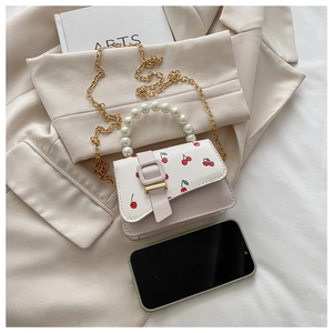 Close-up of pink and white cherry print crossbody bag with pearl handle and gold chain