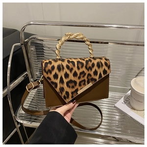 Detail of leopard print crossbody bag with gold metallic handle on a modern display