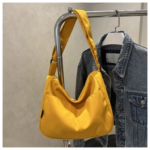Detail of bright yellow crescent tote bag hanging on a hanger with denim jacket background