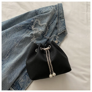 Détail du sac seau noir tissé avec chaîne argentée et accents de perles blanches