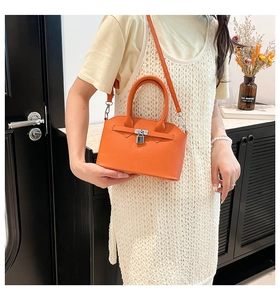 Detail der orangefarbenen Handtasche aus Leder mit Silberverschluss und Schultergurt