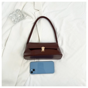 Detailed size view of retro brown leather shoulder bag shown next to a smartphone