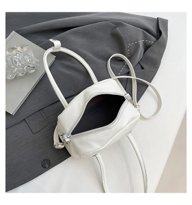 Detailed view of white lychee grain faux leather handbag with silver zipper and strap