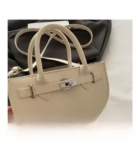 Vue de dessus du sac à main demi-lune crème avec fermoir rotatif et bandoulière cuir