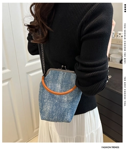 Detail shot of vintage denim crossbody bag with orange leather handle and chain strap