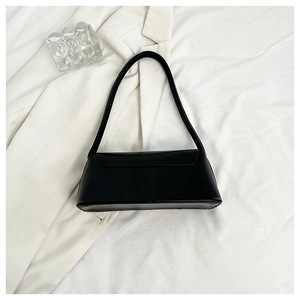 Detailed close-up of a minimalist black rectangle baguette bag on a white textile surface