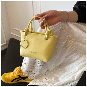 Detail of yellow lychee pattern leather bucket bag with smiley charm and fashion text