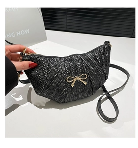 Macro detail of black woven crescent bag with gold bow clasp and metallic zipper