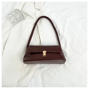 Detail of vintage brown leather underarm bag with elegant gold hardware buckle closure
