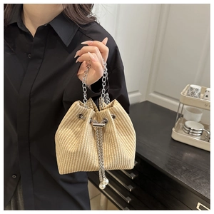 Gros plan du sac seau en paille tressée avec poignée chaîne et cordon de perles