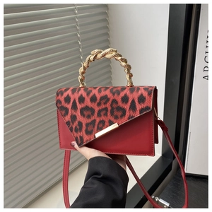 Detail of red leopard print handbag featuring a twisted gold metal handle and shoulder strap