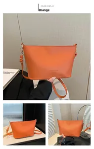 Détail du sac seau orange à motif litchi avec boucles dorées et texte embossé sur le cuir
