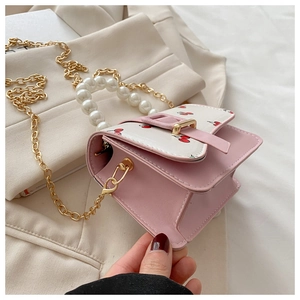 Detail of pink leather mini bag with cherry print, pearl handle and golden chain strap