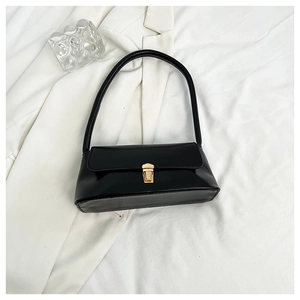 Close-up of minimalist black leather underarm bag with gold metal buckle on white blazer