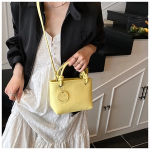 Close-up of yellow lychee pattern mini bucket bag with smile charm and shoulder strap
