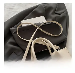 Détail du sac à main crème avec fermeture à verrou rotatif et fine bandoulière réglable
