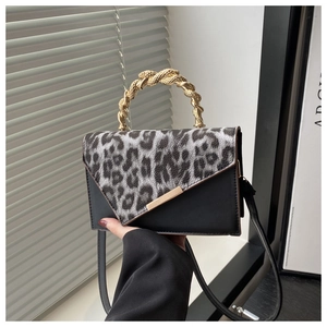 Detail of leopard print拼接bag with a gold twisted metal handle and textured black leather