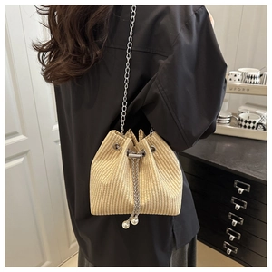 Détail du sac seau tissé avec une élégante chaîne en métal et des accents de perles au cordon
