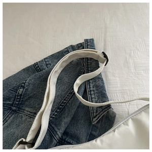 Detail of white padded nylon crossbody bag showing the zipper and adjustable strap
