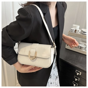 Detail of cream faux crocodile texture shoulder bag with golden horseshoe buckle