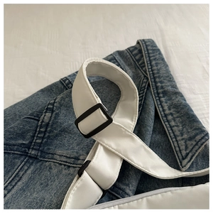 Close-up of adjustable strap with matte black buckle on minimalist white shoulder bag
