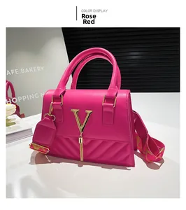 Detail of rose red handbag featuring a gold V-logo with elegant fringe and wide strap