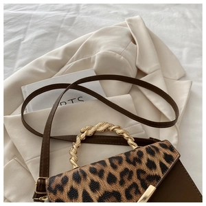 Detail of leopard print patchwork handbag featuring a golden spiral woven metal handle