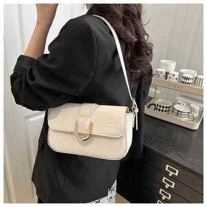 Detail of crocodile embossed cream faux leather shoulder bag with golden horseshoe buckle