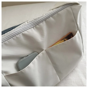 Detail view of white canvas crossbody bag with front pockets showing storage capacity