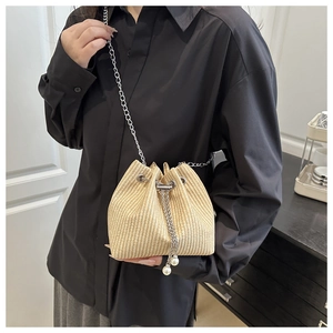 Detail of beige straw bucket bag featuring fine weave and pearl drawstring charms