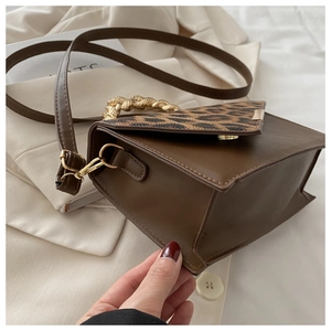 Close-up of leopard print flap and gold chain handle on brown crossbody bag