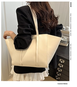 Large cream tote bag shown in a lifestyle model shot with minimalist leather detail