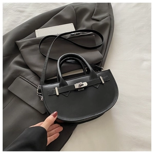 Détail du sac demi-lune noir avec fermoir rotatif argenté sur une veste grise