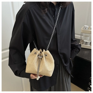 Détail du sac seau tissé beige avec cordon de serrage, chaîne et perles élégantes